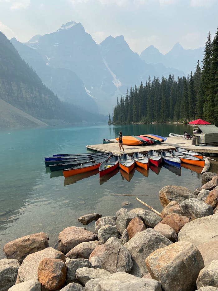 Woman standing on pier with colorful canoes in beautiful Moraine Lake scenery.